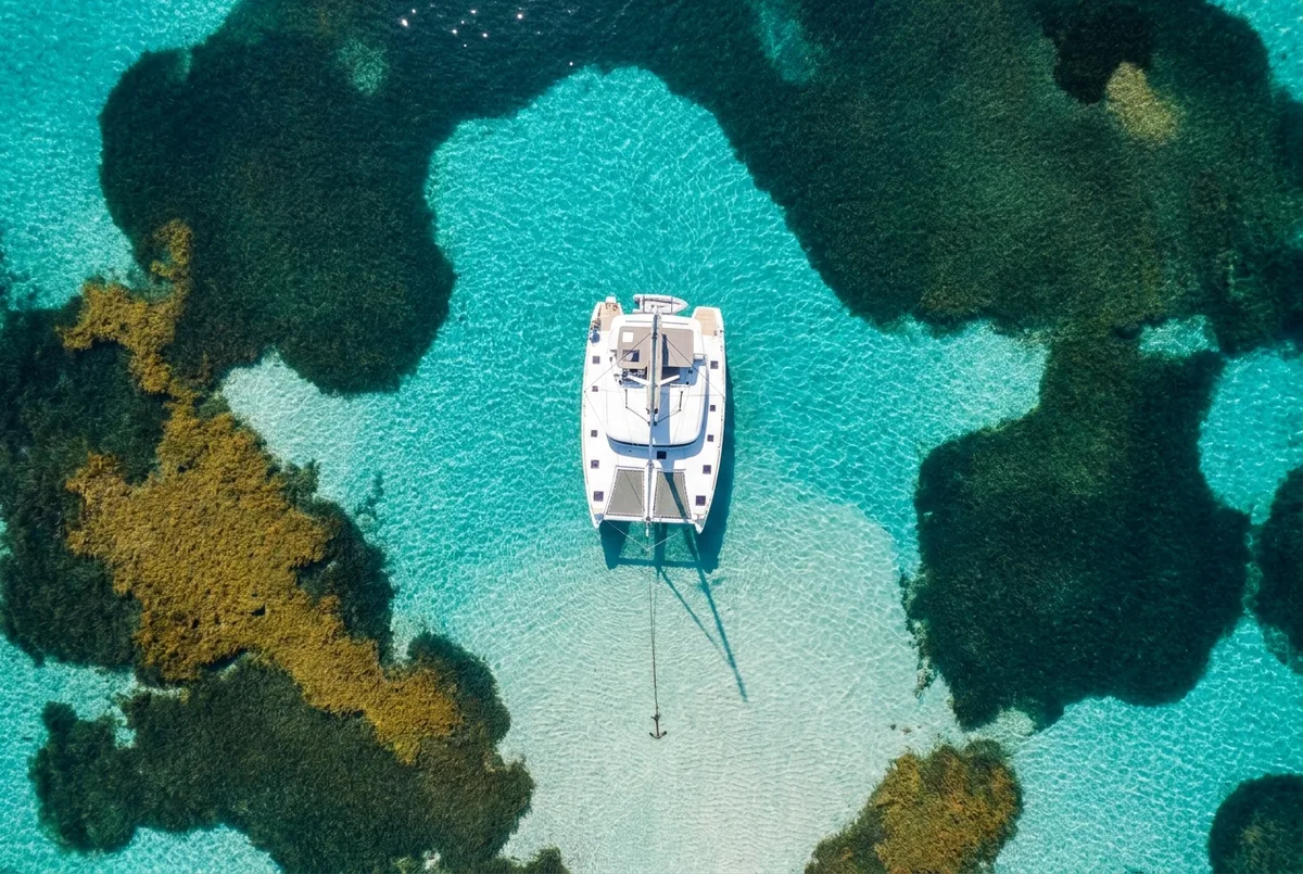 Catamarán fondeado sobre un claro de arena entre praderas de posidonia