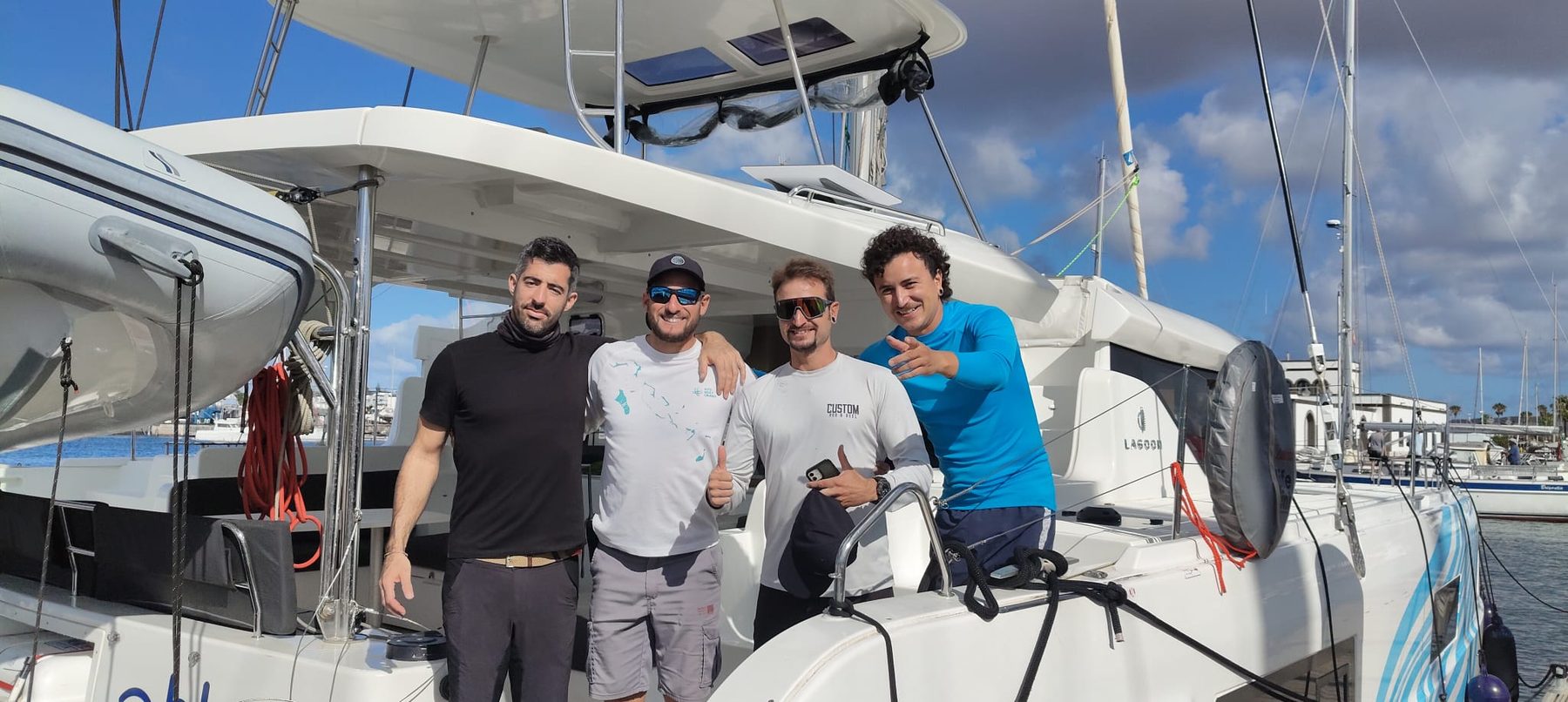 La tripulación del Lagoon 46 en la proa del catamarán, en el puerto, antes de zarpar hacia el Atlántico