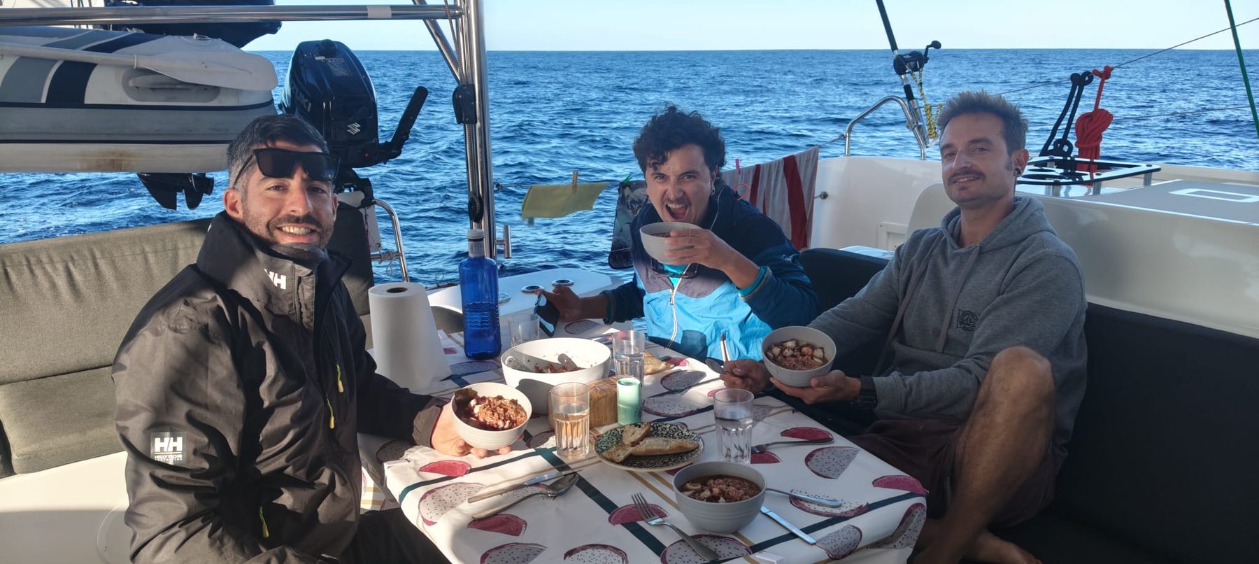 Parte de la tripulación comiendo en la bañera del catamarán en pleno Atlántico